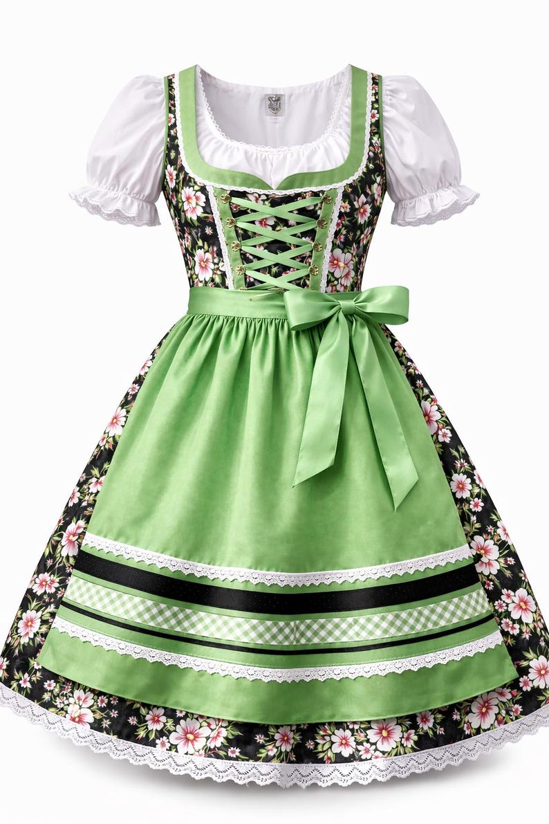 Op de afbeelding: Een traditionele Duitse dirndl jurk. De zwarte lijfje heeft een bloemenpatroon en groene rand, gecombineerd met een witte blouse. De groene schort heeft zwarte en witte linten en kant. Een groene strik siert de taille.
