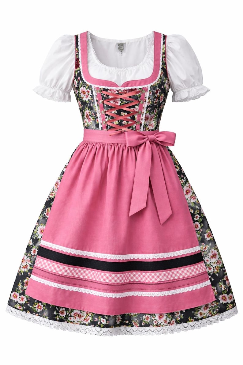 Op de afbeelding: Een traditionele dirndl-jurk met een witte blouse met pofmouwen, een bloemenlijfje en een roze rok met een bijpassende schort. De jurk heeft een roze lintcorset en een roze strik in de taille. De rok heeft witte kanten rand.