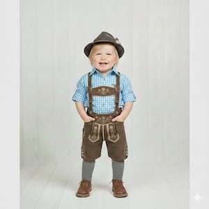 Puede incluir: Un niño con un traje bávaro tradicional. El conjunto incluye una camisa a cuadros azul y blanco, pantalones cortos de cuero marrón con tirantes, un sombrero a juego, calcetines grises y zapatos marrones. El atuendo tiene detalles bordados.