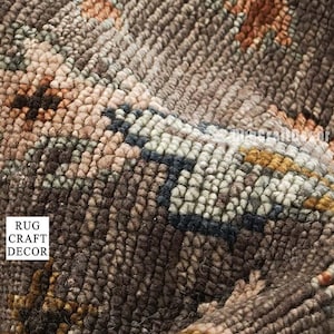 May include: A textured rug featuring a dense loop pile construction in shades of dark brown, tan, and muted orange. The surface displays a repeating pattern of small floral and geometric motifs. The text RUG CRAFT DECOR is visible on the rug.