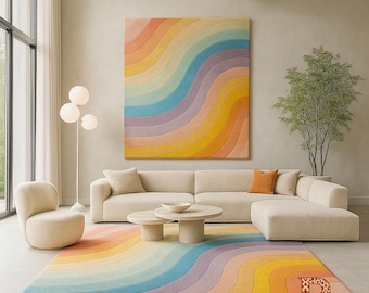 May include: A modern living room featuring a large, colorful rug with a rainbow wave design. The room includes a beige sectional sofa, two round coffee tables, and a matching armchair. A large artwork with a similar rainbow pattern hangs on the wall. The word "RUGSA" is visible.