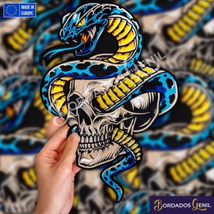 Può includere: Toppa ricamata con un serpente blu e giallo avvolto attorno a un teschio bianco. La testa del serpente è sollevata e i suoi occhi sono aperti. La toppa è realizzata in Europa.