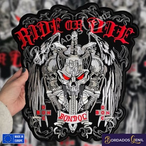 Peut inclure: Patch brodé noir avec un motif de crâne et d'os croisés. Le crâne a des yeux rouges et est entouré de deux épées et de deux ailes. Le texte "Ride or Die" est au-dessus du crâne et le texte "Bondoc" est en dessous du crâne.