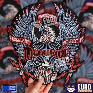 Puede incluir: Parche bordado con un águila con las alas extendidas, un escudo y el texto "LIVE TO RIDE". El diseño incorpora colores rojo, blanco y azul, con las palabras "LEGENDARY MOTORCYCLES" en una pancarta.