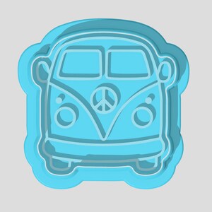 Puede incluir: Un cortador de galletas azul con forma de furgoneta Volkswagen vintage con un símbolo de paz en la parte delantera.