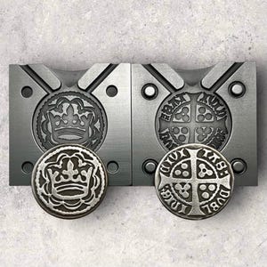 May include: Two metal molds for making coins. The left mold shows a crown with a fleur-de-lis design. The right mold shows a cross with a fleur-de-lis design.