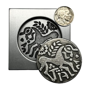 May include: A silver coin with a stylized image of a horse and a sprig of leaves. The coin is in a metal mold with the same image, but in reverse. A silver US Buffalo nickel is also shown.
