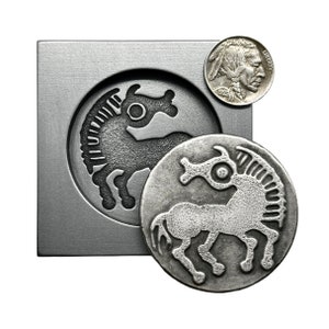 May include: A silver metal coin with a stylized image of a horse. The coin is next to a metal mold with the same image.