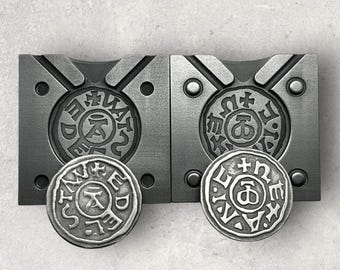 May include: Two silver metal molds for making coins. The molds are made of metal and have a circular design. The molds are open and show the design of the coins that will be made. The coins have a circular design with a cross in the center and the words "DEUS", "REX", "ANNO", and "DOMINI" around the edge.