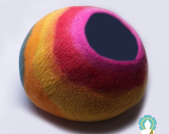May include: A colorful felt cat bed in the shape of a sphere with a large opening. The bed is made of wool felt and is dyed in shades of blue, green, yellow, orange, pink, and red.