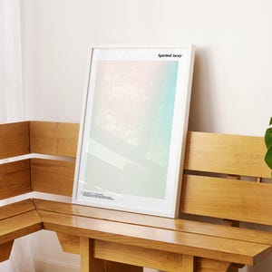 a wooden bench with a framed artwork hanging on it, placed in a room with a window and a plant.