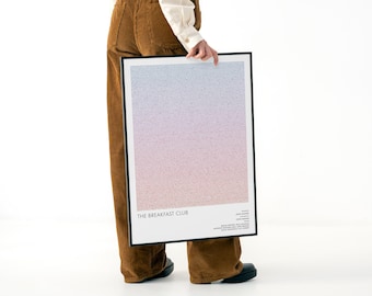 May include: A framed poster with a gradient design in shades of blue, pink, and purple. The poster features the text "THE BREAKFAST CLUB" at the bottom, along with additional text. The frame is black.
