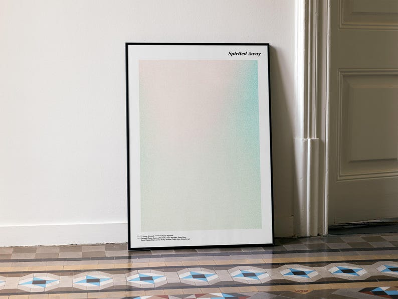 a framed poster with a minimalist design, placed on a tiled floor next to a white door.