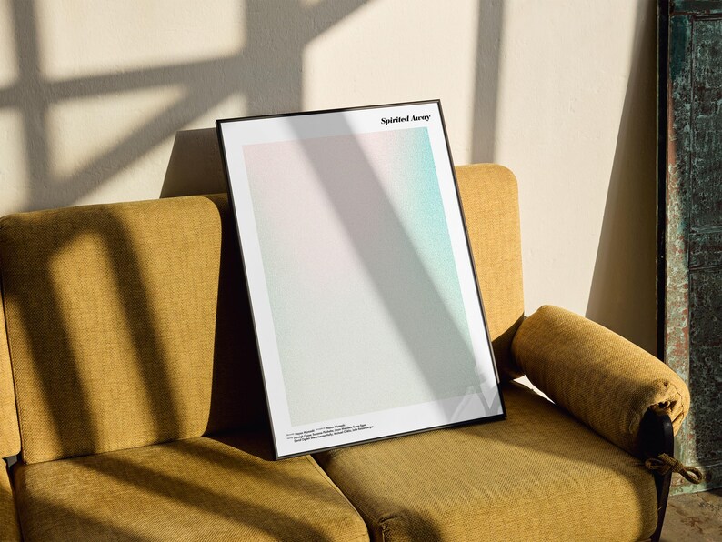 a framed poster with a minimalist design, placed on a yellow couch against a white wall.