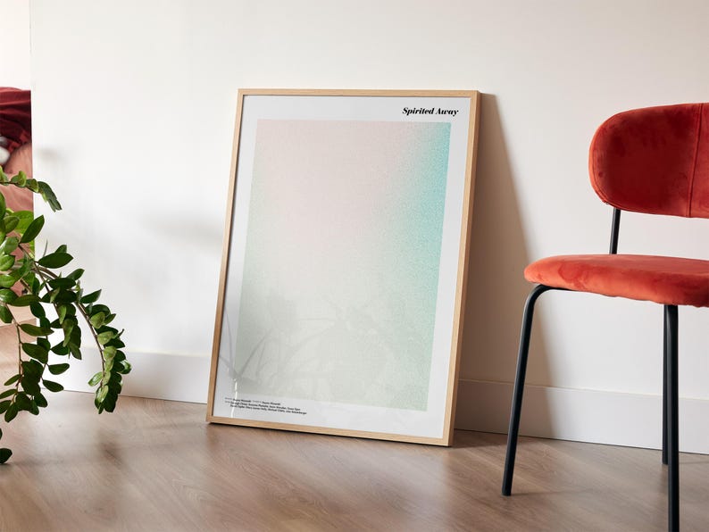 a framed poster with a gradient background, placed on a wooden floor next to a red chair.