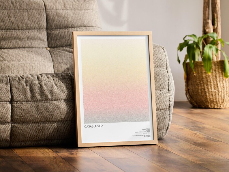 Pu&ograve; includere: Una stampa artistica incorniciata con un design sfumato nei toni del giallo, rosa e grigio. La stampa &egrave; intitolata "Casablanca" ed &egrave; esposta in una cornice di legno chiaro. L'opera d'arte &egrave; appoggiata a un divano grigio imbottito, con una pianta in un cesto di vimini.