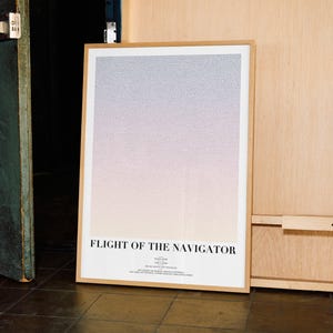 May include: A framed poster with the title "FLIGHT OF THE NAVIGATOR" in a minimalist design. The artwork features a gradient of colors, transitioning from light purple to peach. The poster is in a light brown wooden frame.