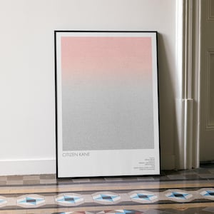 Puede incluir: Un póster enmarcado con un diseño degradado de rosa a gris. La impresión, titulada "CITIZEN KANE", se exhibe contra una pared blanca. La obra de arte está en un marco negro.
