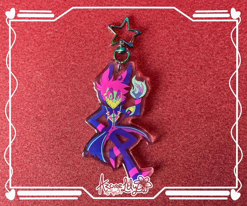 May include: A colorful acrylic keychain featuring a cartoon character with a magenta and blue color scheme. The character is holding a blue flame. The keychain has a star-shaped clasp and the text "Azure Lily".