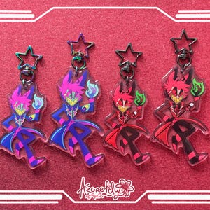 May include: Four acrylic keychains featuring a cartoon character with a wide grin, holding a flame. The keychains have star-shaped clasps and come in purple, blue, red, and black color schemes. The background is a textured red surface.