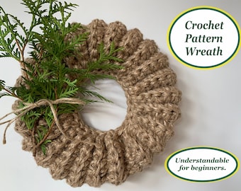 May include: A brown crocheted wreath with a green sprig of greenery on top. The wreath is made with a thick, textured yarn. The text "Crochet Pattern Wreath" and "Understandable for beginners." is written on the image.