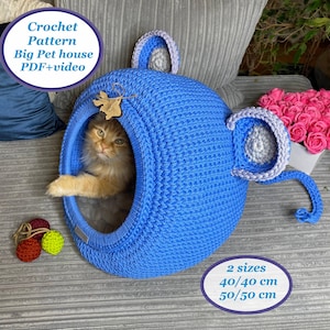 May include: A blue crochet pet house with a cat inside. The house has a round shape with ear-like details and a handle. The text on the image says "Crochet Pattern Big Pet house PDF+video" and "2 sizes 40/40 cm 50/50 cm".