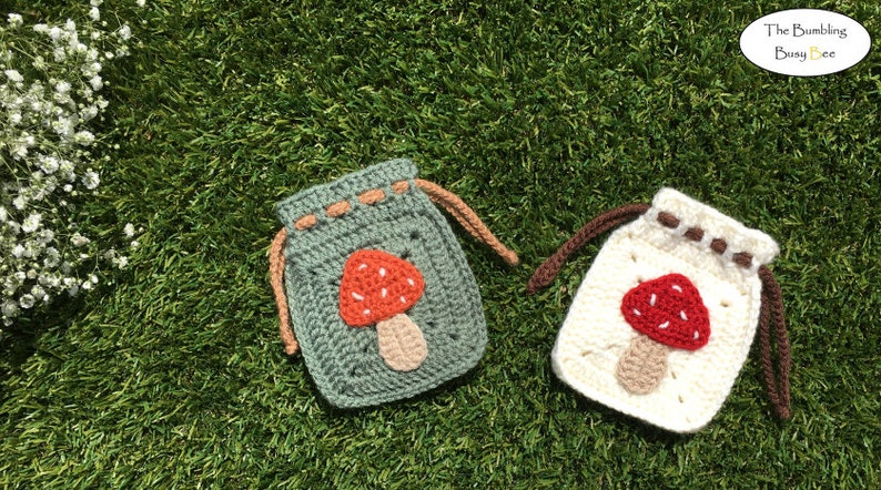 May include: Two crocheted drawstring bags with mushroom designs. One bag is green with a red and white mushroom, the other is white with a red and white mushroom.