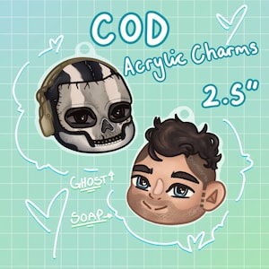 May include: Two acrylic charms featuring characters from Call of Duty. One charm depicts a skull-faced character, and the other shows a man's face. The charms are approximately 6.35 cm in size, with the words "COD Acrylic Charms" written above.