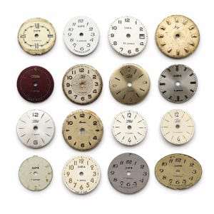 Op de afbeelding: Een verzameling van zestien vintage horlogefaces, elk met een uniek ontwerp en verschillende gradaties van slijtage. De faces tonen cijfers, tekst en merknamen, met een reeks kleuren.