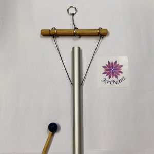 以下が含まれることがあります： 木製のハンマーと木製の吊り下げバーが付いた銀色の金属製のチャイム。チャイムは黒い紐で吊り下げられており、上部に銀色のリングが付いています。