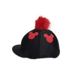 May include: Black baseball cap featuring a red pom-pom and three red Mickey Mouse head shapes. The cap has a curved peak and is set against a white backdrop.