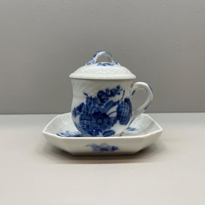 Peut inclure: Une tasse à thé en porcelaine blanche avec un couvercle, une anse et une soucoupe assortie. La tasse et la soucoupe sont décorées de motifs floraux bleus. Le couvercle a un motif texturé. La tasse à thé repose sur une soucoupe carrée.