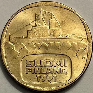 May include: A gold-colored Finnish coin featuring an icebreaker ship sailing through ice floes. The coin reads "SUOMI FINLAND 1991" and has a small "M" mint mark.