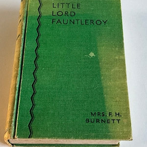May include: A green hardcover book with the title "LITTLE LORD FAUNTLEROY" and the author "MRS. F.H. BURNETT" printed on the front cover.