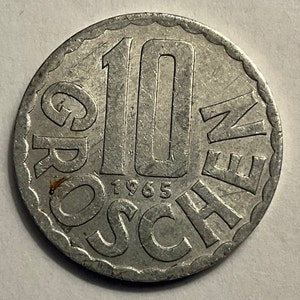 May include: A silver 10 Groschen coin from Austria, dated 1965. The coin features the denomination "10 Groschen" written in a circle around the number "10".