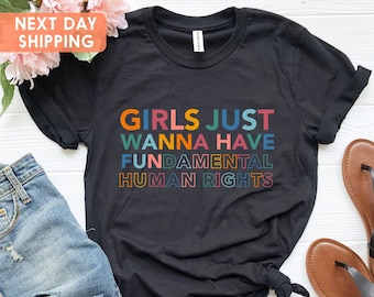 May include: Black t-shirt with the text "Girls Just Wanna Have Fundamental Human Rights" in rainbow colors.