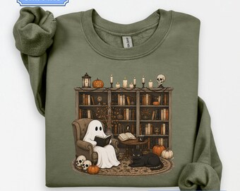 Può includere: Una felpa girocollo color verde militare con una stampa grafica raffigurante un fantasma che legge un libro su una poltrona, un gatto nero, una libreria piena di libri, zucche, candele e teschi. L'etichetta interna riporta il marchio Gildan.