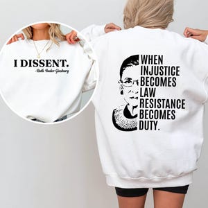 May include: White sweatshirt with a black and white image of Ruth Bader Ginsburg and the text "When injustice becomes law resistance becomes duty."