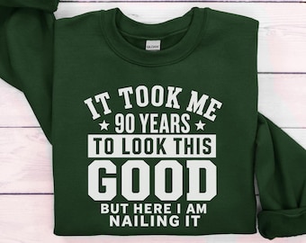 Può includere: Una felpa a girocollo a maniche lunghe color verde bosco con testo stampato in bianco che recita: IT TOOK ME 90 YEARS TO LOOK THIS GOOD BUT HERE I AM NAILING IT. Il capo presenta un'etichetta del marchio Gildan all'interno del colletto.