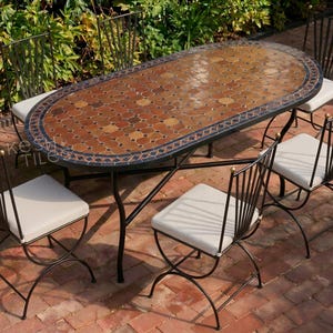 May include: An outdoor dining set featuring a mosaic-tiled oval table and four matching chairs. The table has a black metal frame and a decorative tile top with brown, orange, and blue hues. The chairs have white cushions and black metal frames.