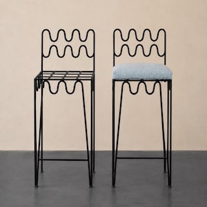 Puede incluir: Dos taburetes de bar altos con marcos de metal negro que presentan un diseño ondulado y serpenteante en los respaldos y faldones. Un taburete tiene un asiento de rejilla abierta, mientras que el otro cuenta con un cojín azul claro texturizado.