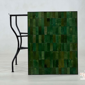 Pode incluir: Uma mesa com tampo de azulejos verdes e estrutura de metal preto. Os azulejos est&atilde;o dispostos em um padr&atilde;o de mosaico. A mesa &eacute; feita pela Kesh Tiles.