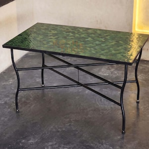 Peut inclure: Table basse rectangulaire avec un dessus en mosaïque verte et des pieds en métal noir. Le dessus de la table présente un motif de carreaux verts et bruns. Les pieds sont incurvés et ont une conception entrecroisée, d'une hauteur d'environ 46 cm.