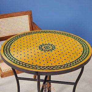 May include: A round table with a yellow and green mosaic tile top. The table has a black metal frame and is 75 cm in diameter.