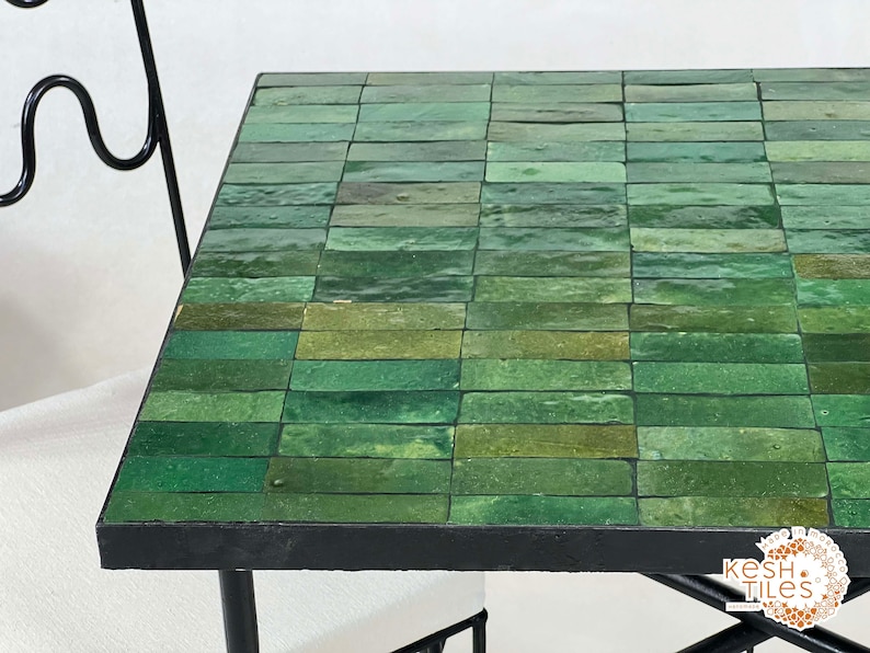 Pode incluir: Uma mesa com tampo de azulejos verdes e moldura de metal preto. Os azulejos est&atilde;o dispostos em forma de grade e t&ecirc;m um acabamento brilhante.