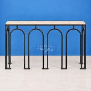 May include: A console table featuring a rectangular beige stone top with a speckled pattern and a black metal base. The base consists of four vertical arched supports connected by horizontal bars. The text KESH TILES is visible in white.