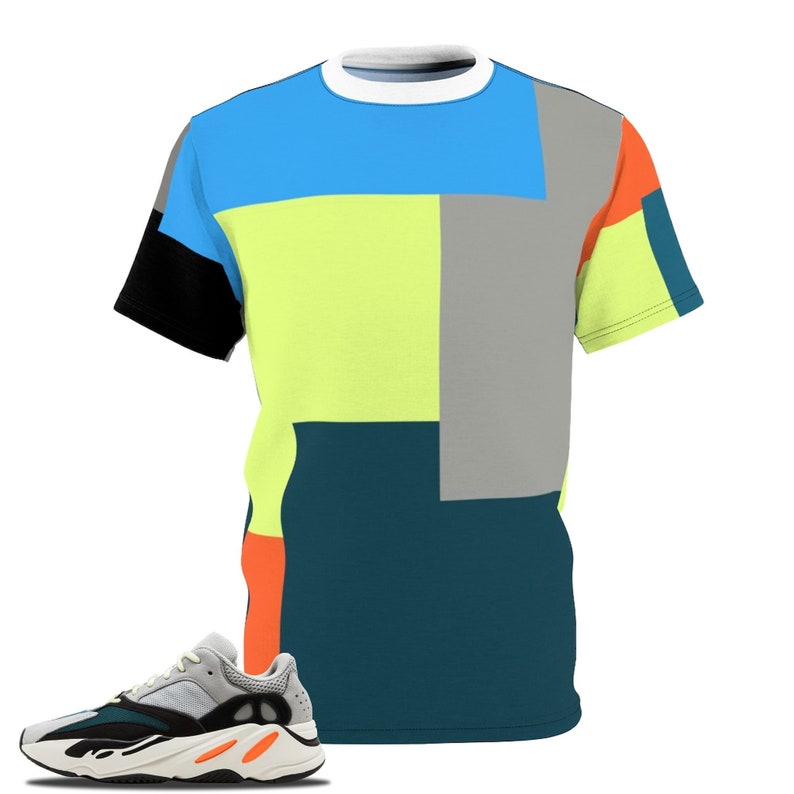 May include: A vibrant t-shirt featuring a geometric pattern in blue, yellow, grey, orange, and black. A pair of grey, black, and orange trainers is next to the shirt. The shirt has a white collar and short sleeves.