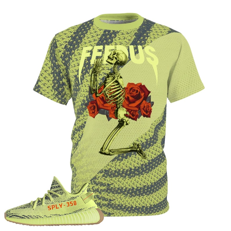 Peut inclure: T-shirt vert clair avec un motif r&eacute;p&eacute;titif et le mot "FEEDUS" en blanc. Le t-shirt pr&eacute;sente un squelette agenouill&eacute; avec des roses rouges. Une basket vert clair et marron avec le texte "SPLY-350" est au premier plan.