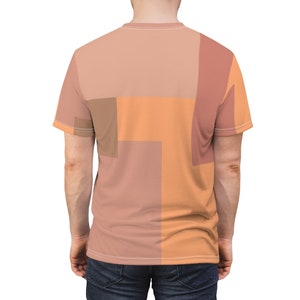 K&ouml;nnte beinhalten: Ein T-Shirt mit kurzen &Auml;rmeln und einem geometrischen Muster in den Farben Pfirsich, Orange und Braun. Das Shirt hat einen Rundhalsausschnitt und eine lockere Passform.