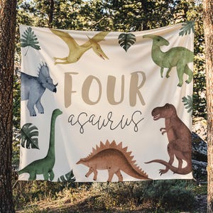 May include: A beige banner with dinosaur illustrations and the text "FOUR a-saurus". The banner features a variety of dinosaurs in shades of green, brown, and blue, with green leaf accents.